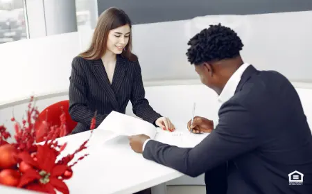 Man filling out tenant application at desk with woman on other side.